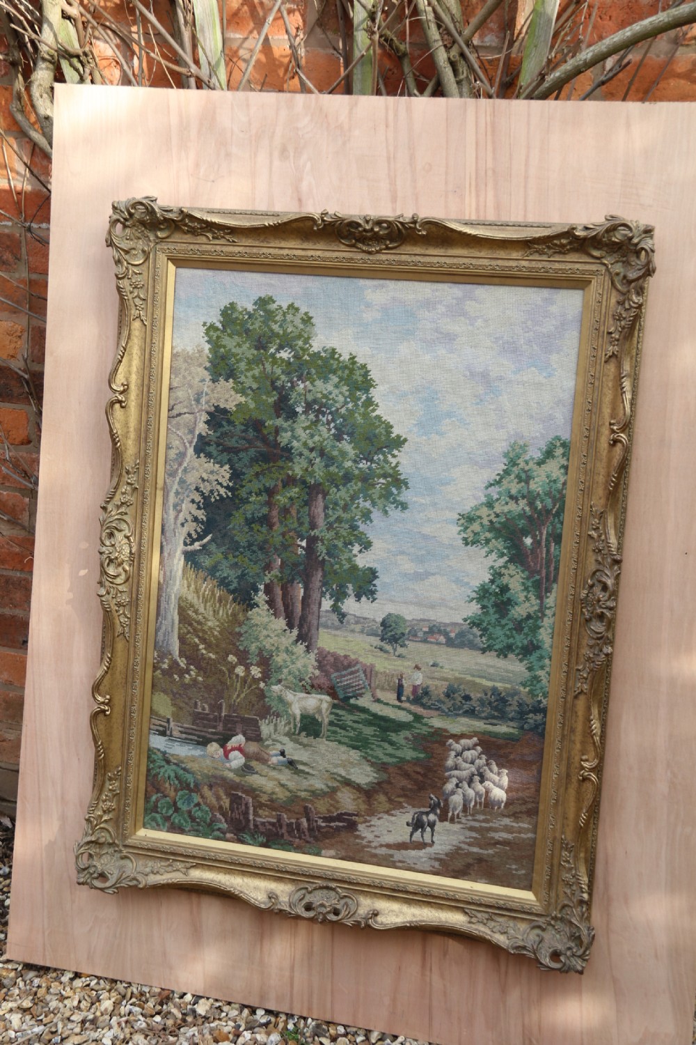 A large framed woolwork needlepoint tapestry depicting a pastoral landscape scene enclosed in a heavily ornamented giltwood frame. View VI