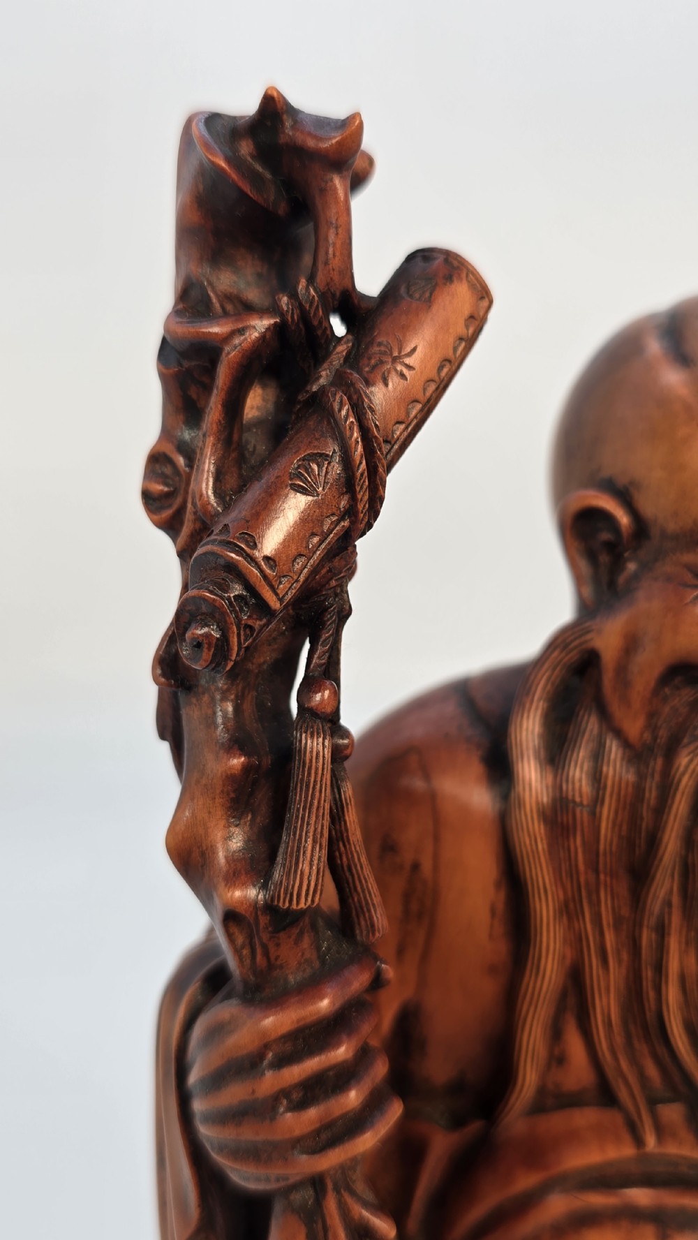 A Japanese carved boxwood okimono figure depicting Fukurokuju with a high forehead, long beard, flowing robes, and holding a gnarled staff. View XIV