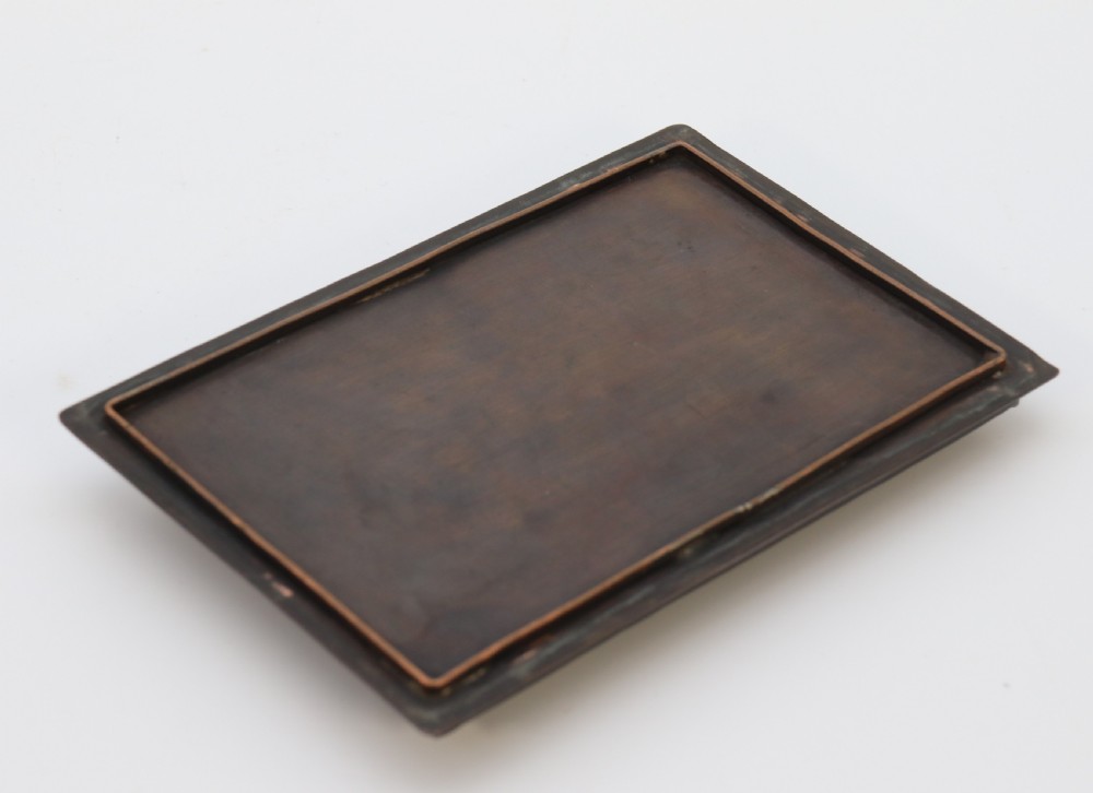 A rectangular dark patinated copper box featuring repousse fruit motifs on the lid, stylized foliage on the front face, bracket feet, and side drop ring handles. View IX