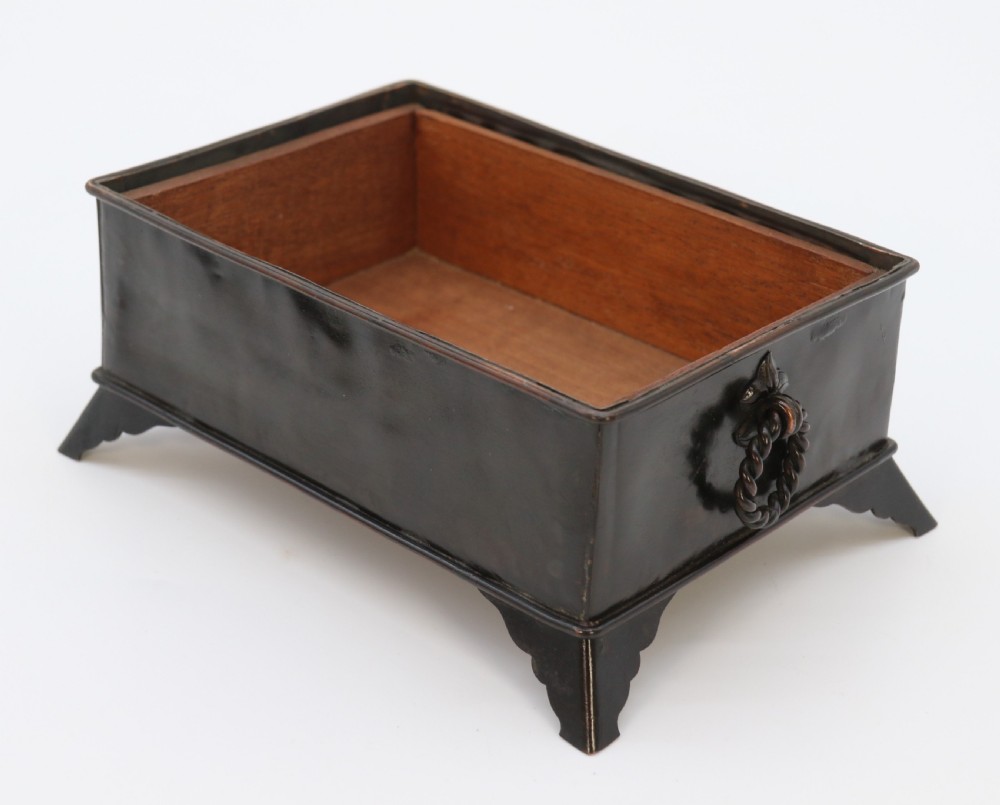 A rectangular dark patinated copper box featuring repousse fruit motifs on the lid, stylized foliage on the front face, bracket feet, and side drop ring handles. View XV