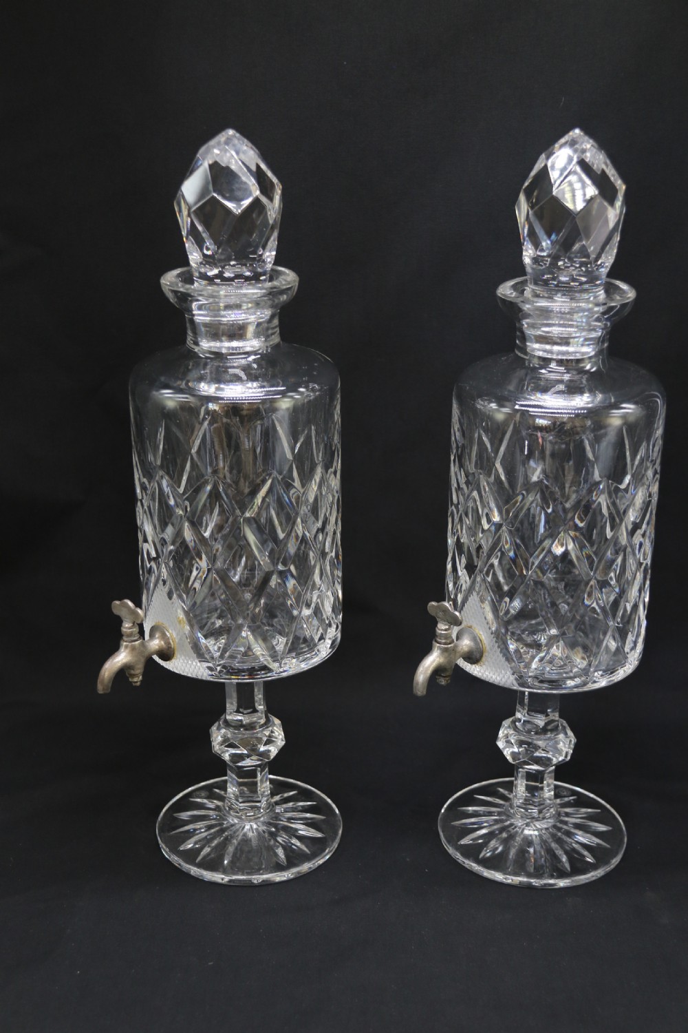 A set of five cut crystal perfume display bottles with faceted stoppers, diamond cut bodies, and silver spigots. View II