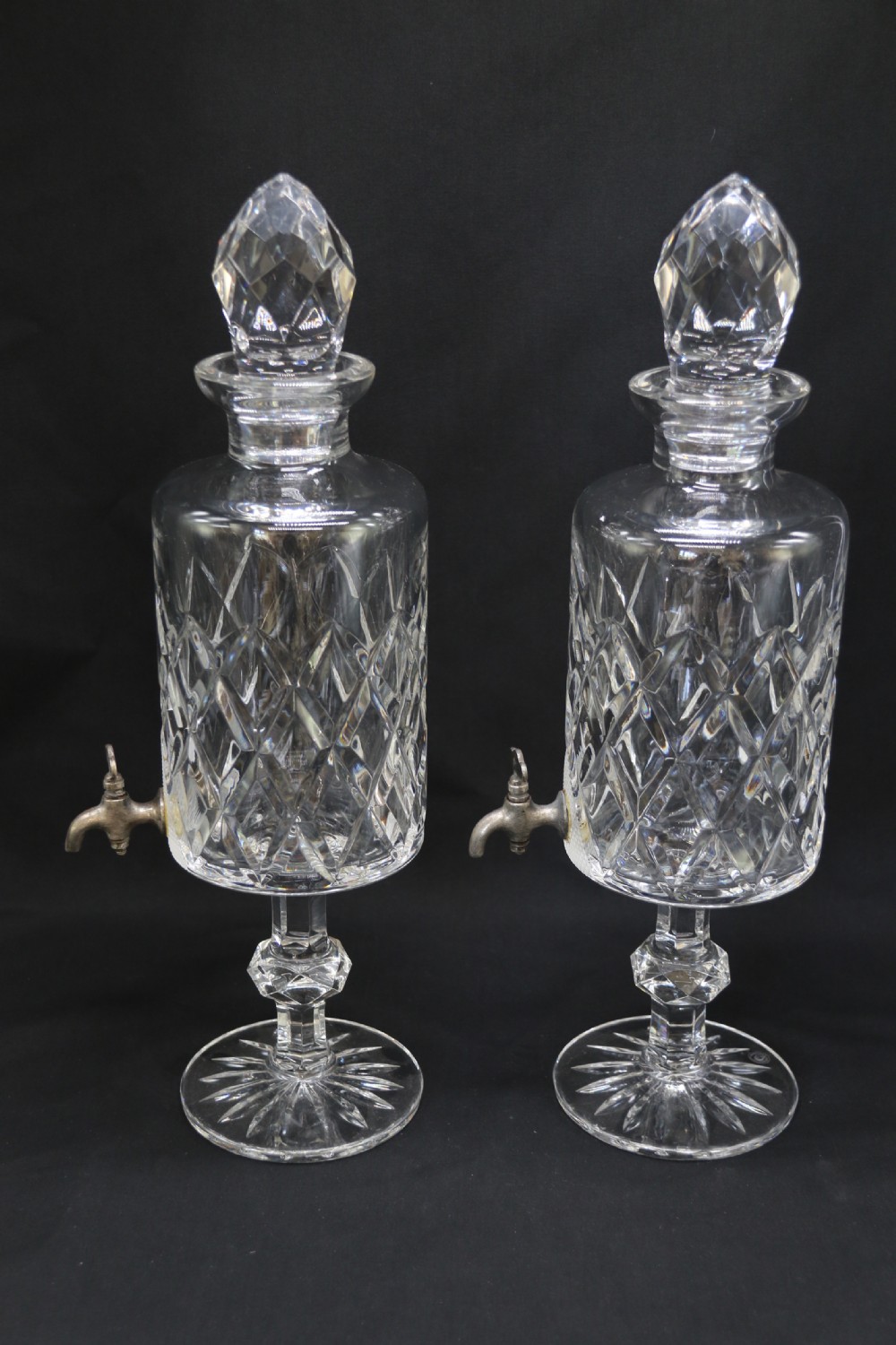 A set of five cut crystal perfume display bottles with faceted stoppers, diamond cut bodies, and silver spigots. View III