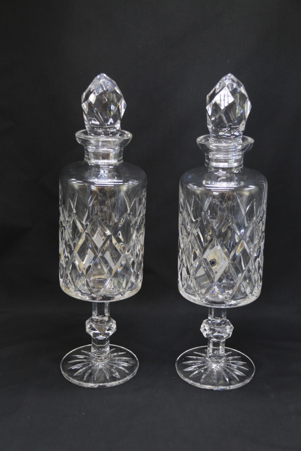 A set of five cut crystal perfume display bottles with faceted stoppers, diamond cut bodies, and silver spigots. View V