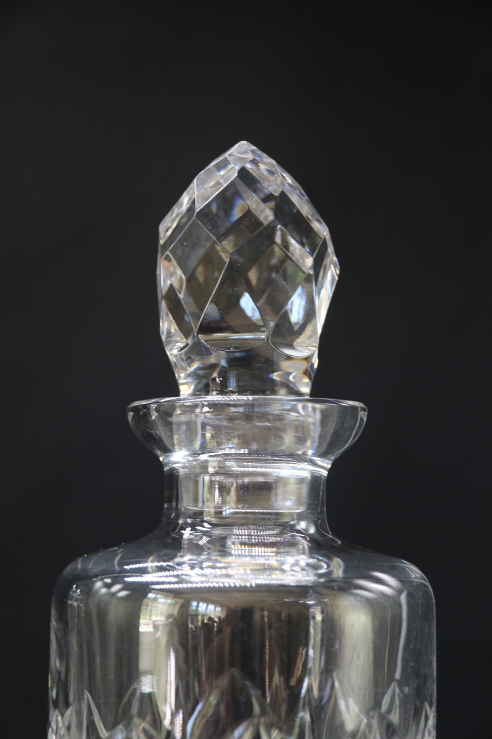 A set of five cut crystal perfume display bottles with faceted stoppers, diamond cut bodies, and silver spigots. View X