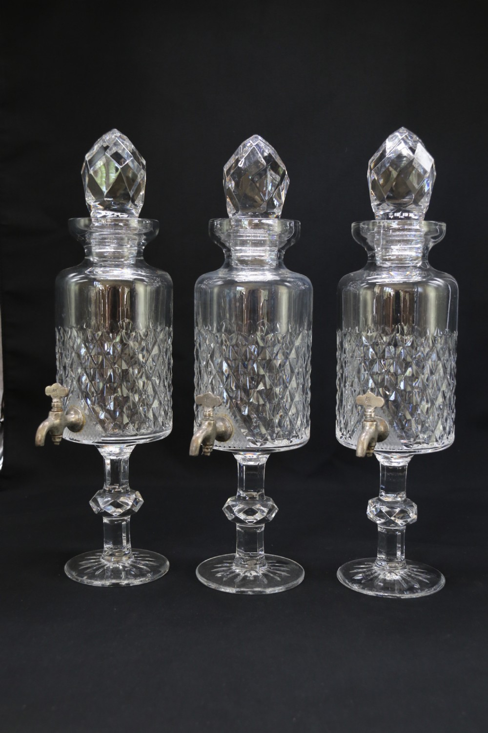 A set of five cut crystal perfume display bottles with faceted stoppers, diamond cut bodies, and silver spigots. View XIII