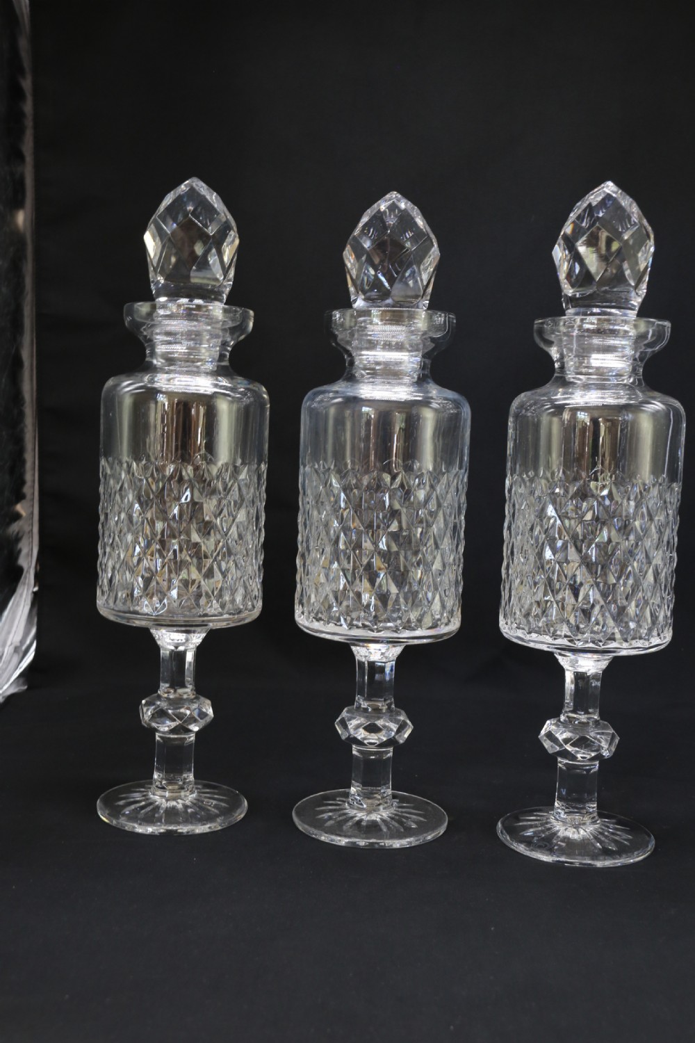 A set of five cut crystal perfume display bottles with faceted stoppers, diamond cut bodies, and silver spigots. View XVI