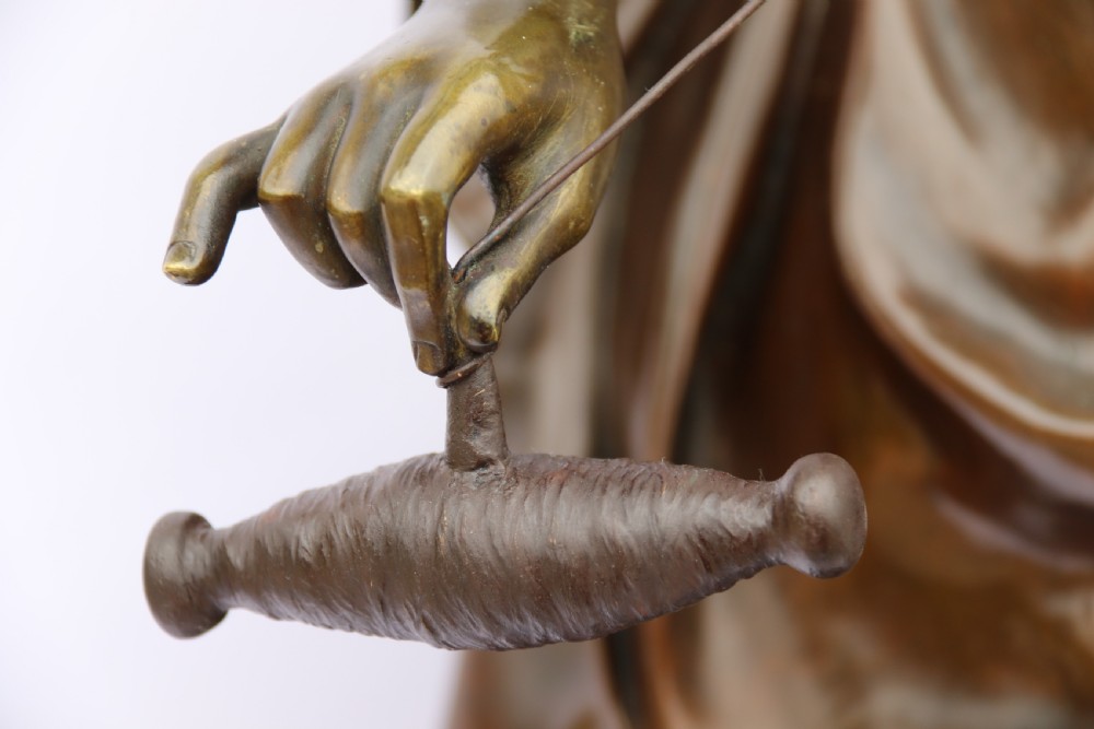 A late nineteenth-century patinated bronze sculpture depicting a woman holding a spinning distaff beside a young child clinging to her skirt. View X