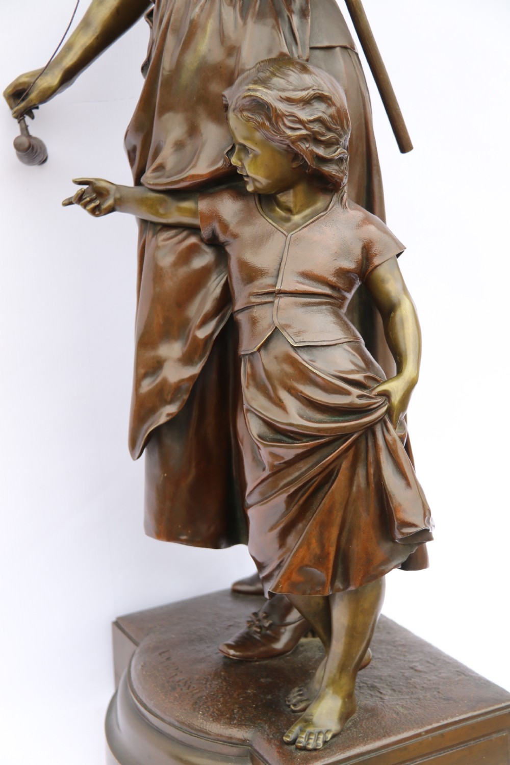 A late nineteenth-century patinated bronze sculpture depicting a woman holding a spinning distaff beside a young child clinging to her skirt. View XXI