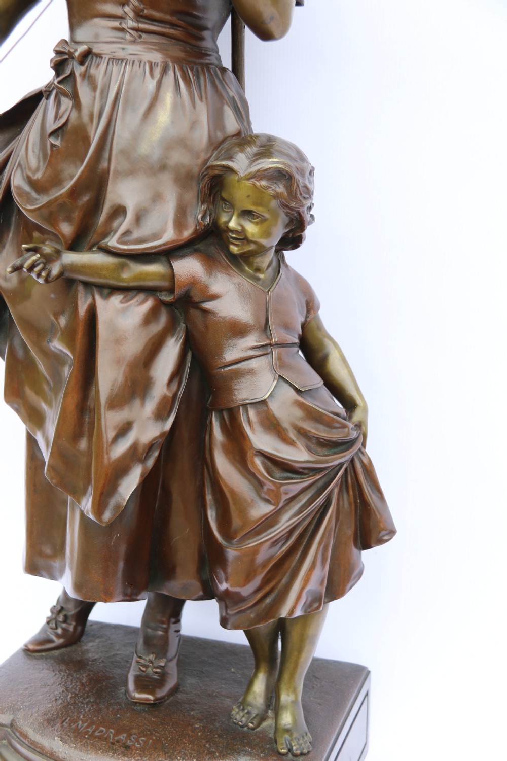 A late nineteenth-century patinated bronze sculpture depicting a woman holding a spinning distaff beside a young child clinging to her skirt. View XXV