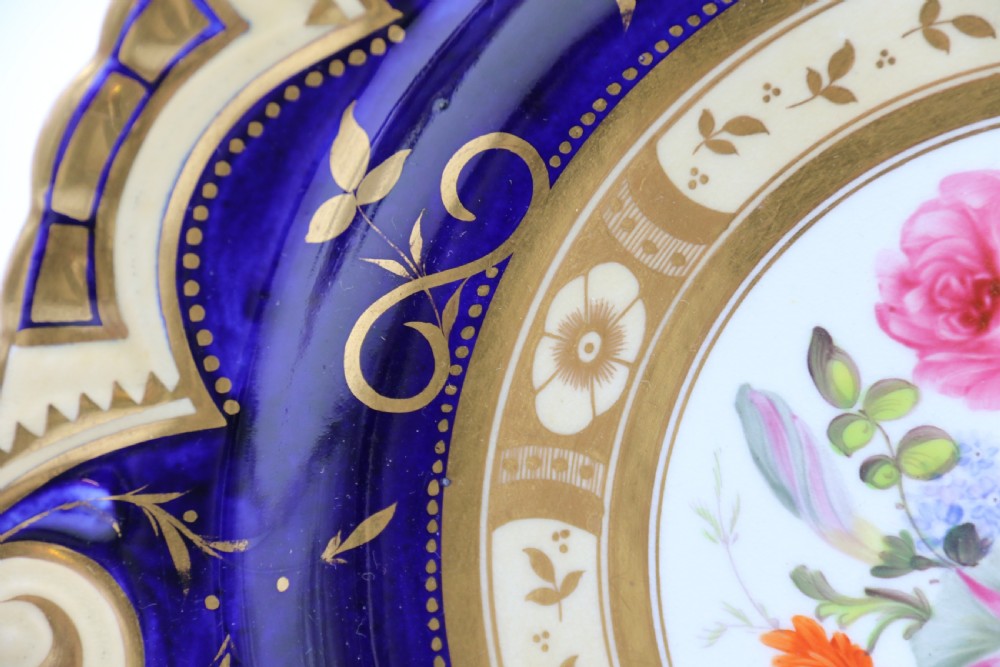 An antique circular English porcelain cabinet plate featuring a cobalt blue and gold scroll border surrounding a central hand-painted floral bouquet. View IX