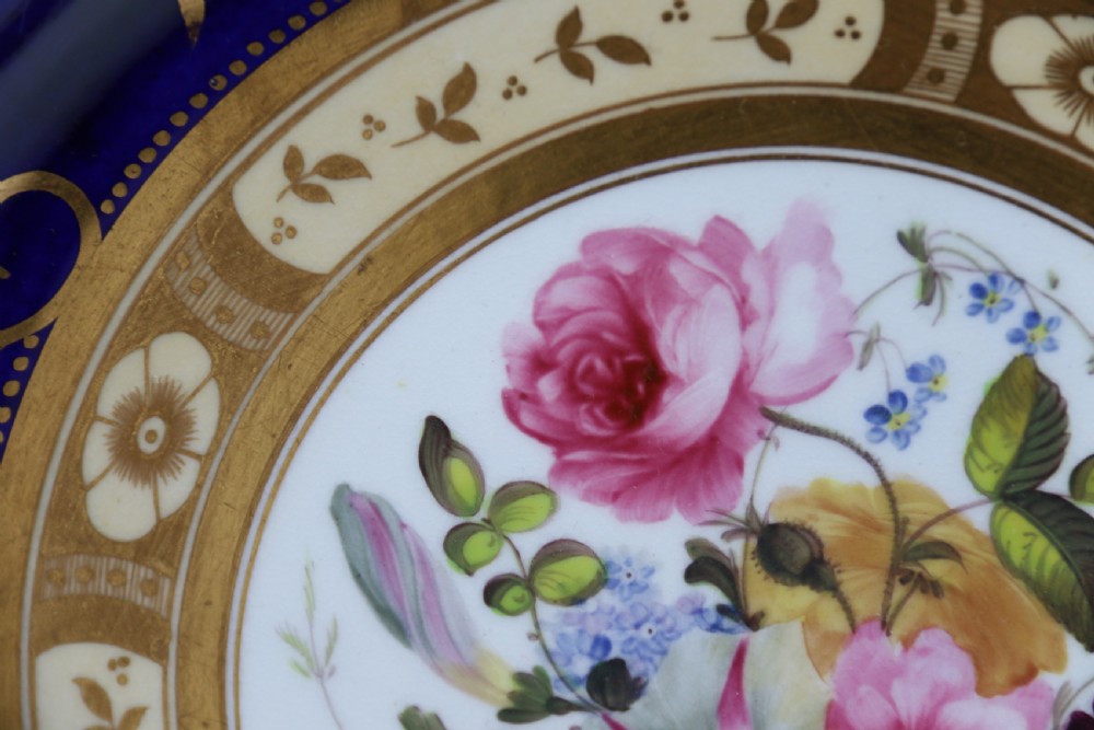 An antique circular English porcelain cabinet plate featuring a cobalt blue and gold scroll border surrounding a central hand-painted floral bouquet. View XI
