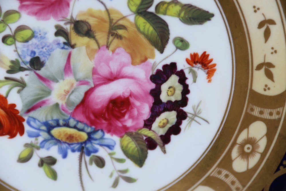 An antique circular English porcelain cabinet plate featuring a cobalt blue and gold scroll border surrounding a central hand-painted floral bouquet. View XII