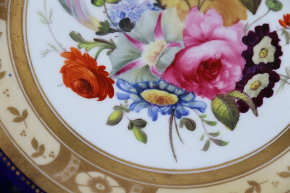 An antique circular English porcelain cabinet plate featuring a cobalt blue and gold scroll border surrounding a central hand-painted floral bouquet. View XIII