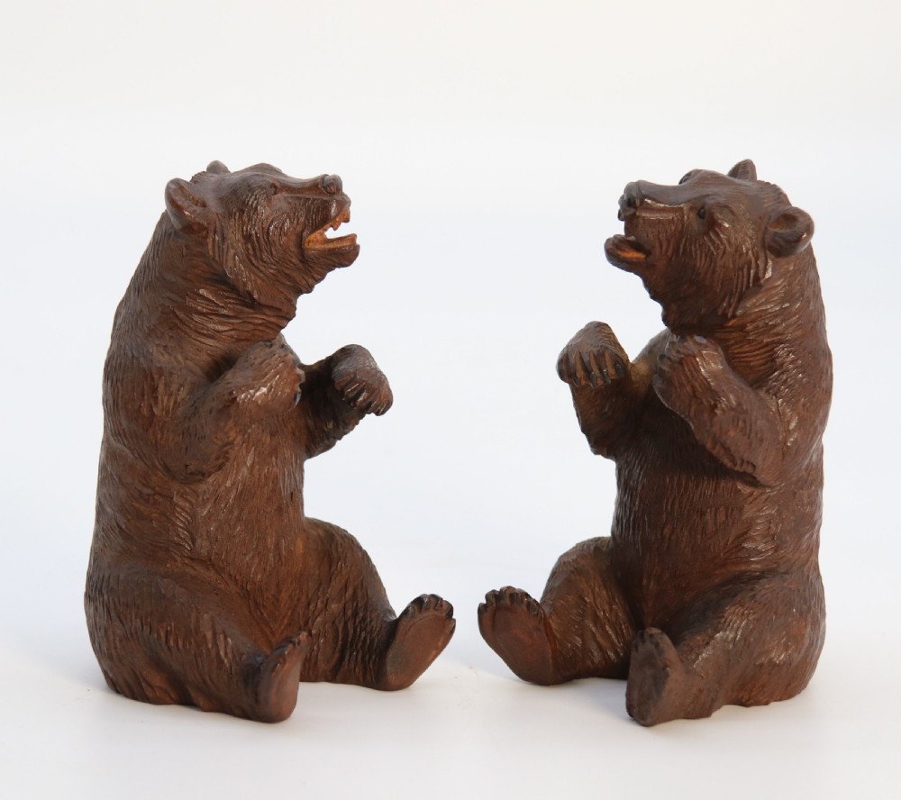 A pair of hand-carved dark brown linden wood Black Forest bears depicted sitting on their haunches with open jaws. View III