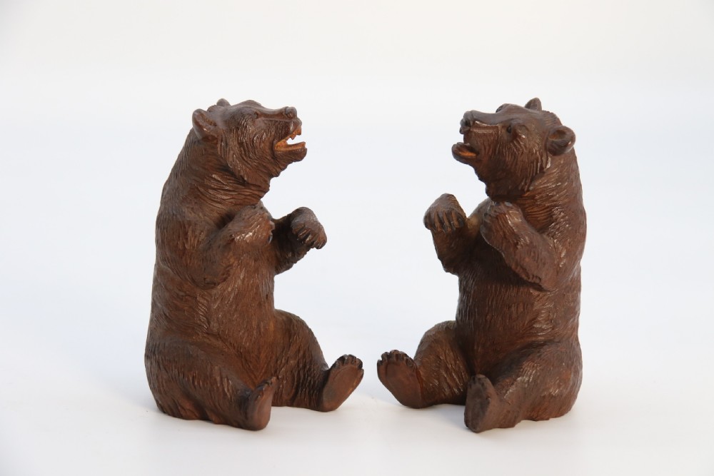 A pair of hand-carved dark brown linden wood Black Forest bears depicted sitting on their haunches with open jaws. View V