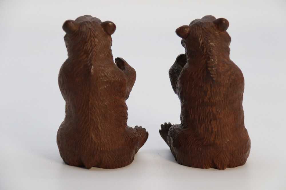 A pair of hand-carved dark brown linden wood Black Forest bears depicted sitting on their haunches with open jaws. View VII