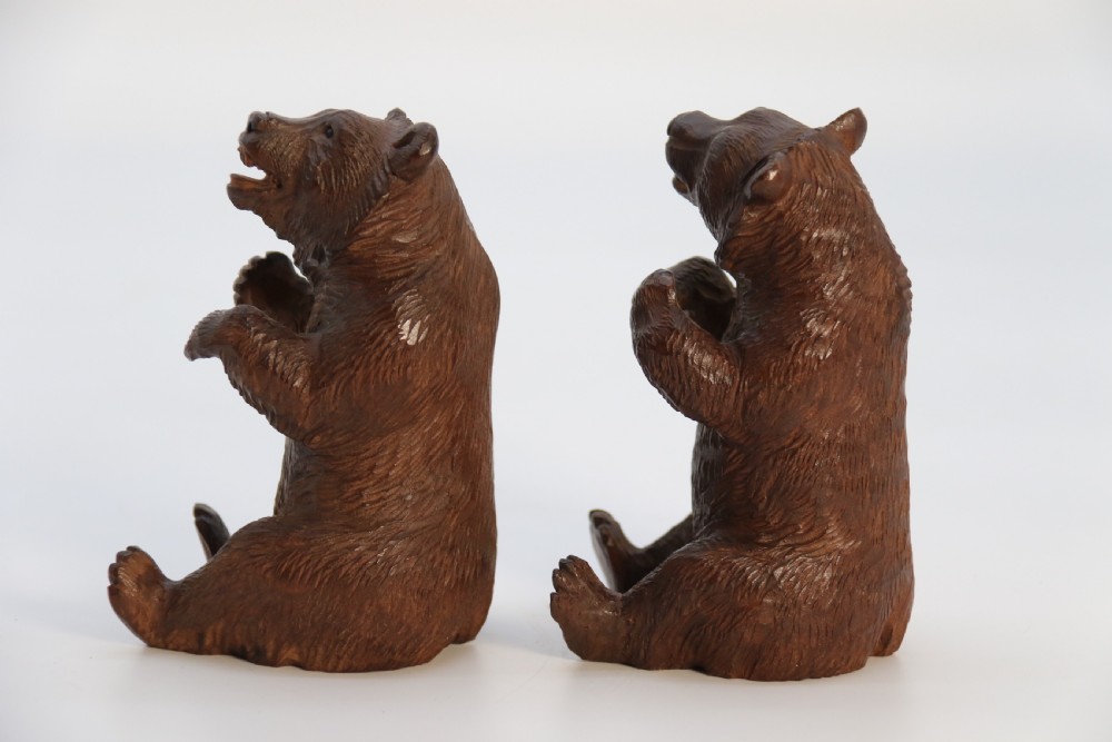 A pair of hand-carved dark brown linden wood Black Forest bears depicted sitting on their haunches with open jaws. View VIII