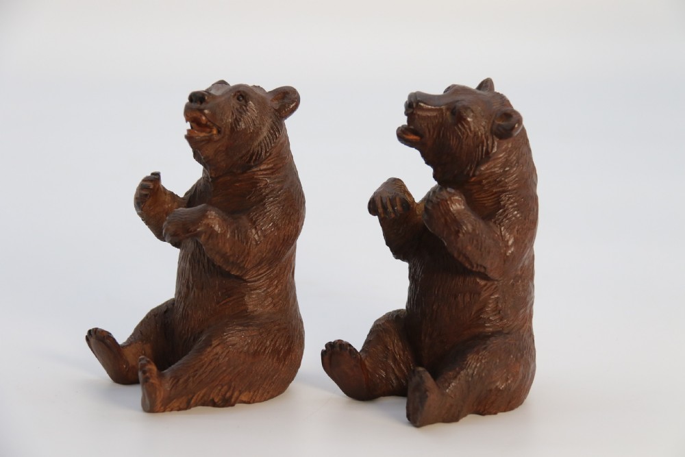 A pair of hand-carved dark brown linden wood Black Forest bears depicted sitting on their haunches with open jaws. View IX