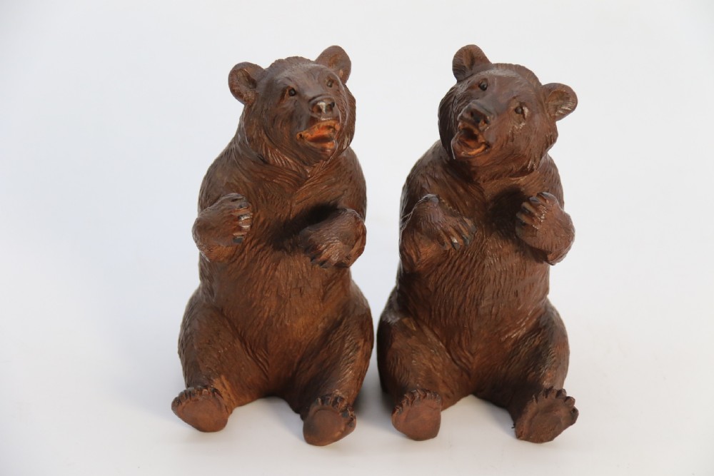 A pair of hand-carved dark brown linden wood Black Forest bears depicted sitting on their haunches with open jaws. View X