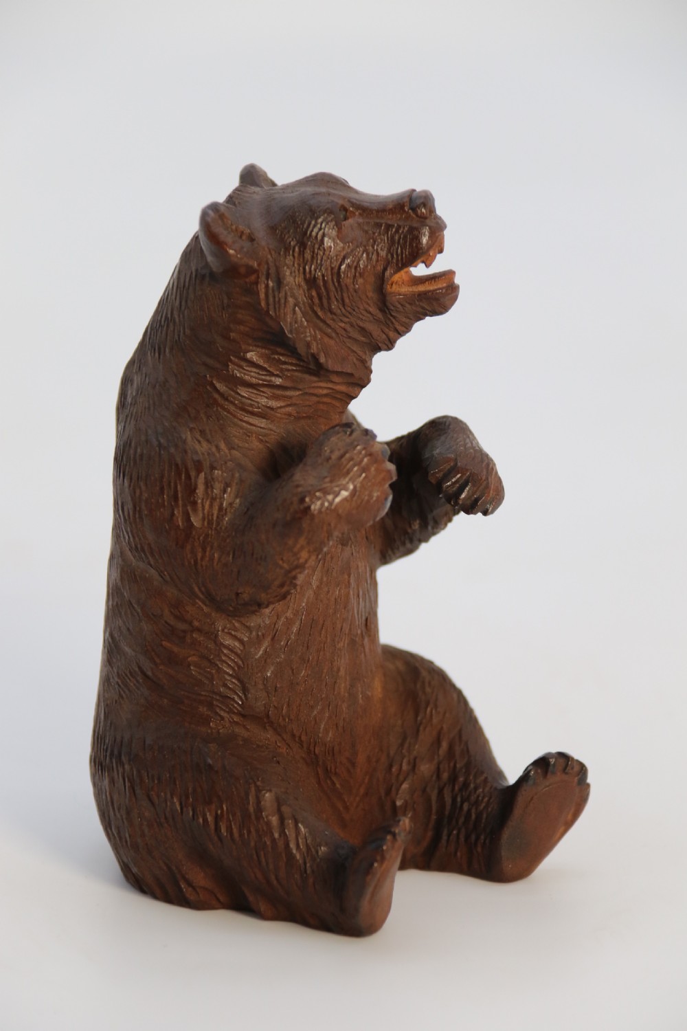 A pair of hand-carved dark brown linden wood Black Forest bears depicted sitting on their haunches with open jaws. View XIX
