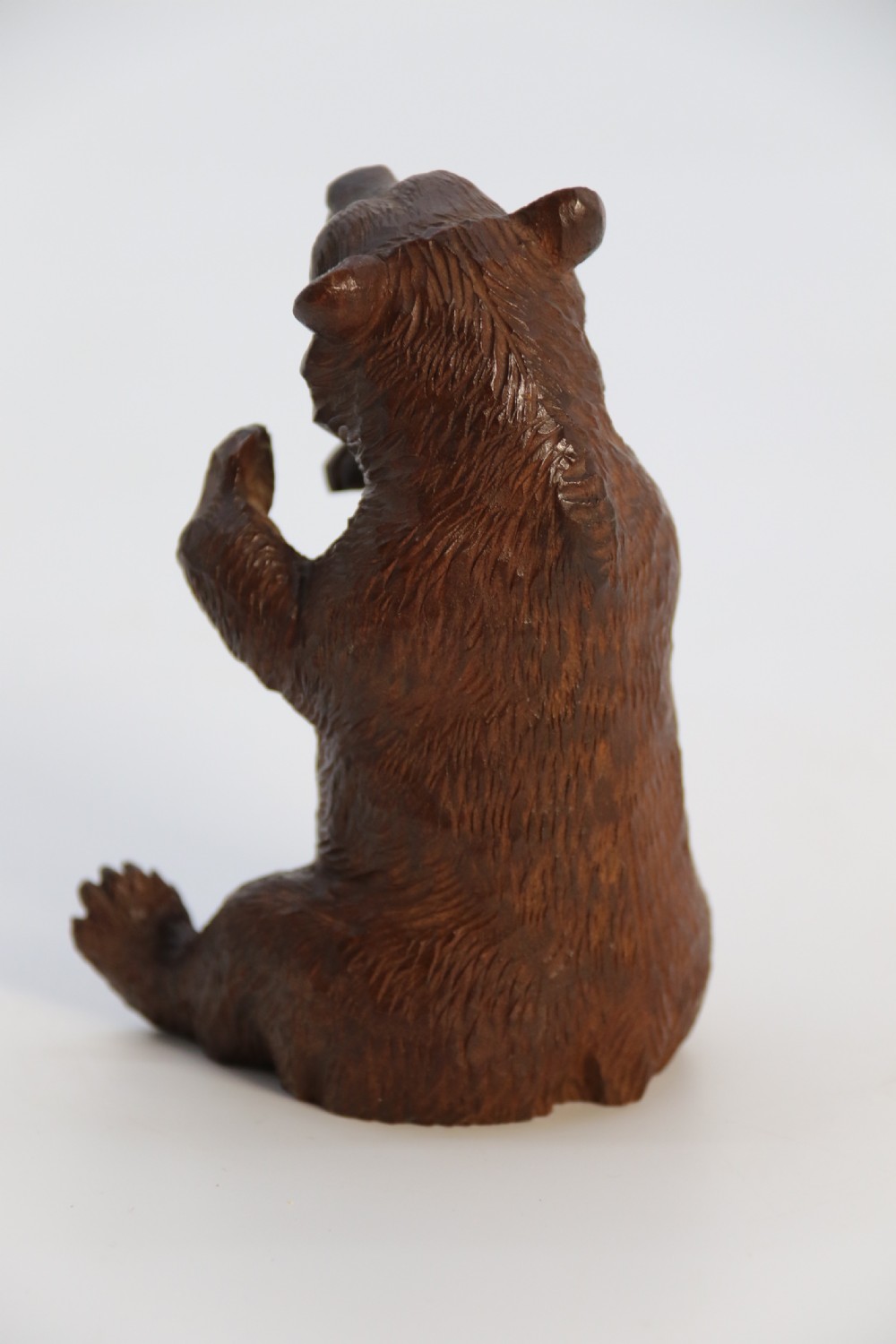 A pair of hand-carved dark brown linden wood Black Forest bears depicted sitting on their haunches with open jaws. View XXVII
