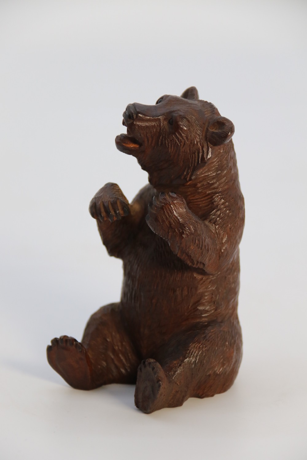 A pair of hand-carved dark brown linden wood Black Forest bears depicted sitting on their haunches with open jaws. View XXIX