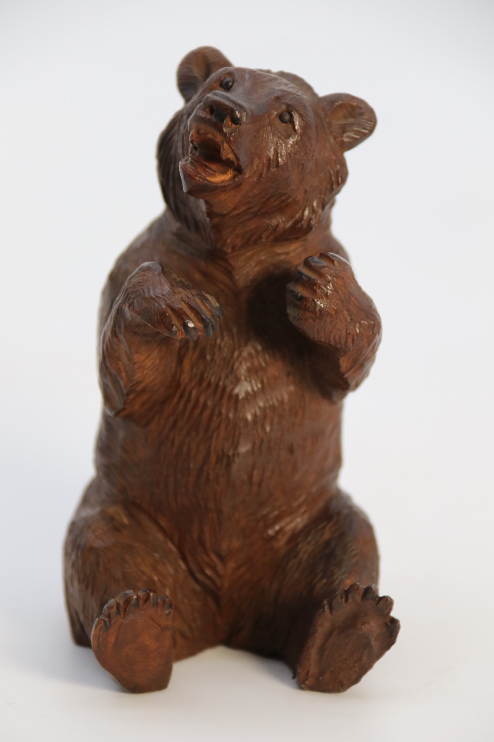 A pair of hand-carved dark brown linden wood Black Forest bears depicted sitting on their haunches with open jaws. View XXX