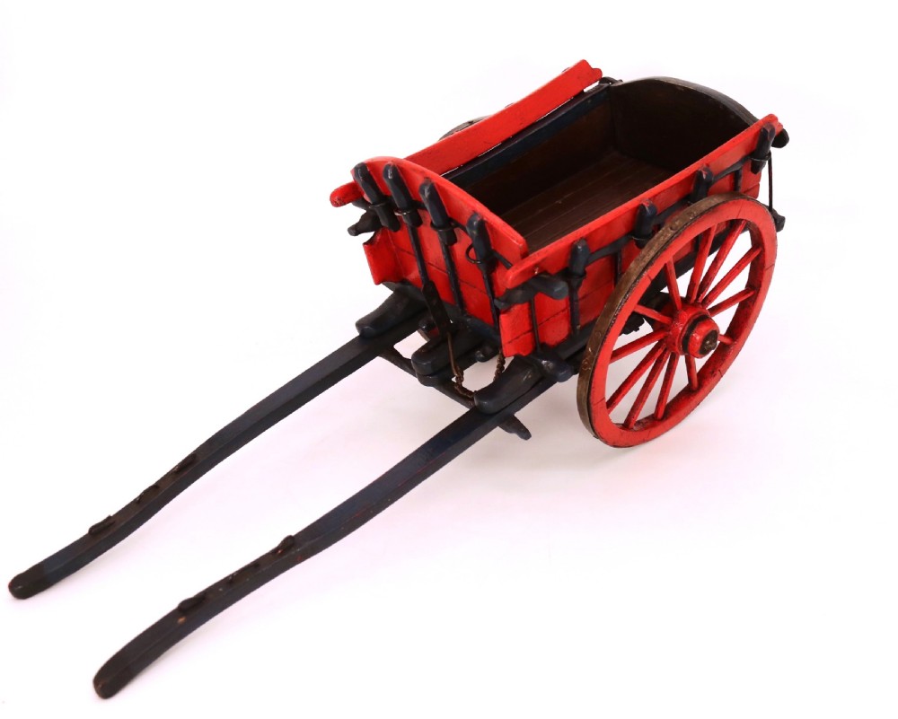A detailed handmade wooden scale model of an 18th-century farm cart featuring red painted sides, dark blue framing and shafts, and spoked red wheels. View VI