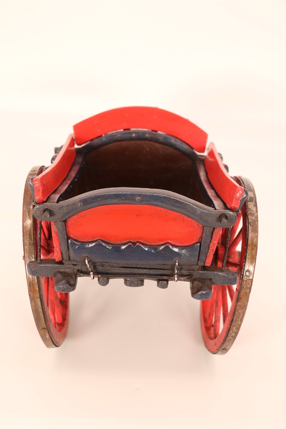 A detailed handmade wooden scale model of an 18th-century farm cart featuring red painted sides, dark blue framing and shafts, and spoked red wheels. View VII