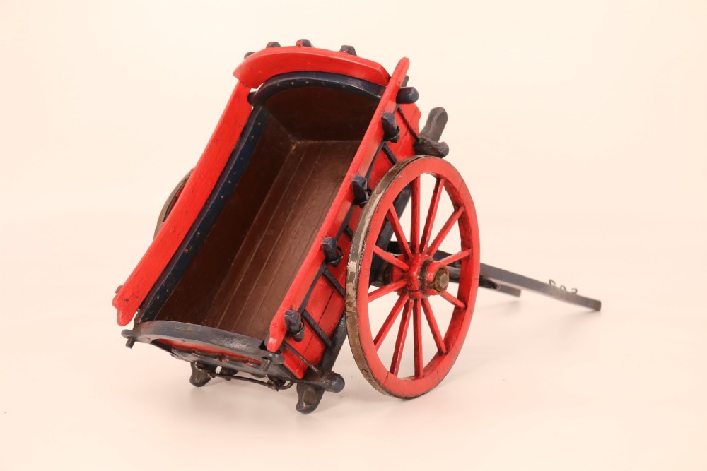 A detailed handmade wooden scale model of an 18th-century farm cart featuring red painted sides, dark blue framing and shafts, and spoked red wheels. View VIII