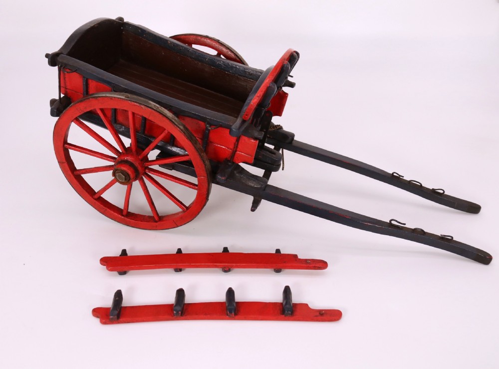 A detailed handmade wooden scale model of an 18th-century farm cart featuring red painted sides, dark blue framing and shafts, and spoked red wheels. View IX
