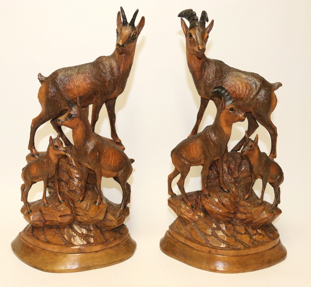 A pair of hand-carved wooden sculptures depicting ibex and chamois with offspring on carved rocky bases. View II