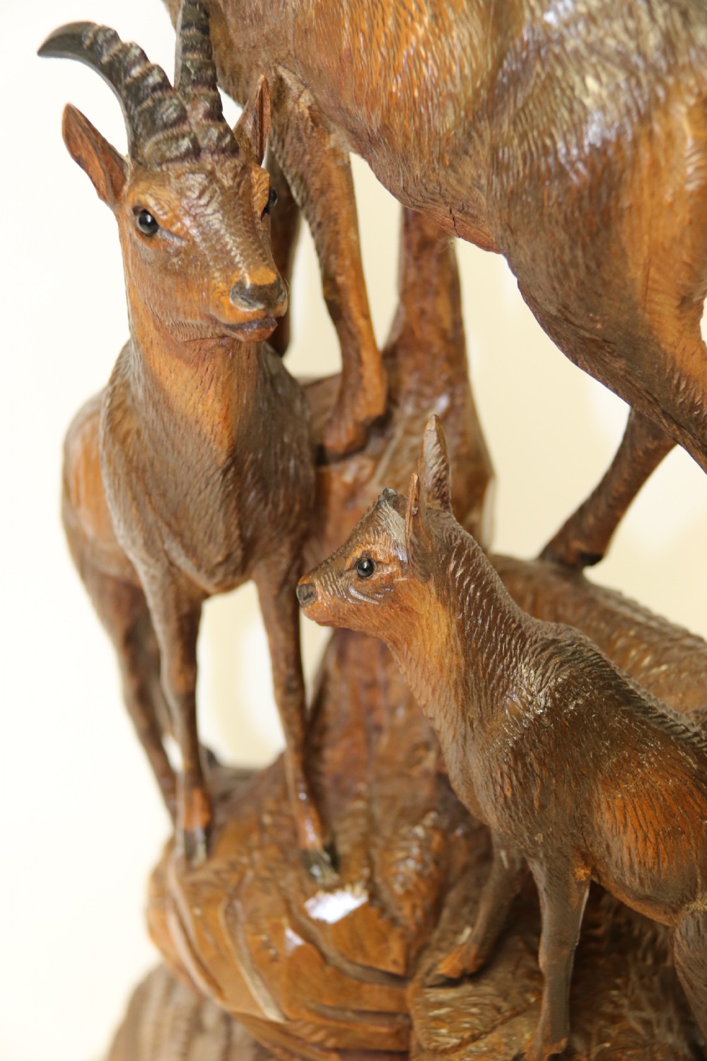 A pair of hand-carved wooden sculptures depicting ibex and chamois with offspring on carved rocky bases. View III