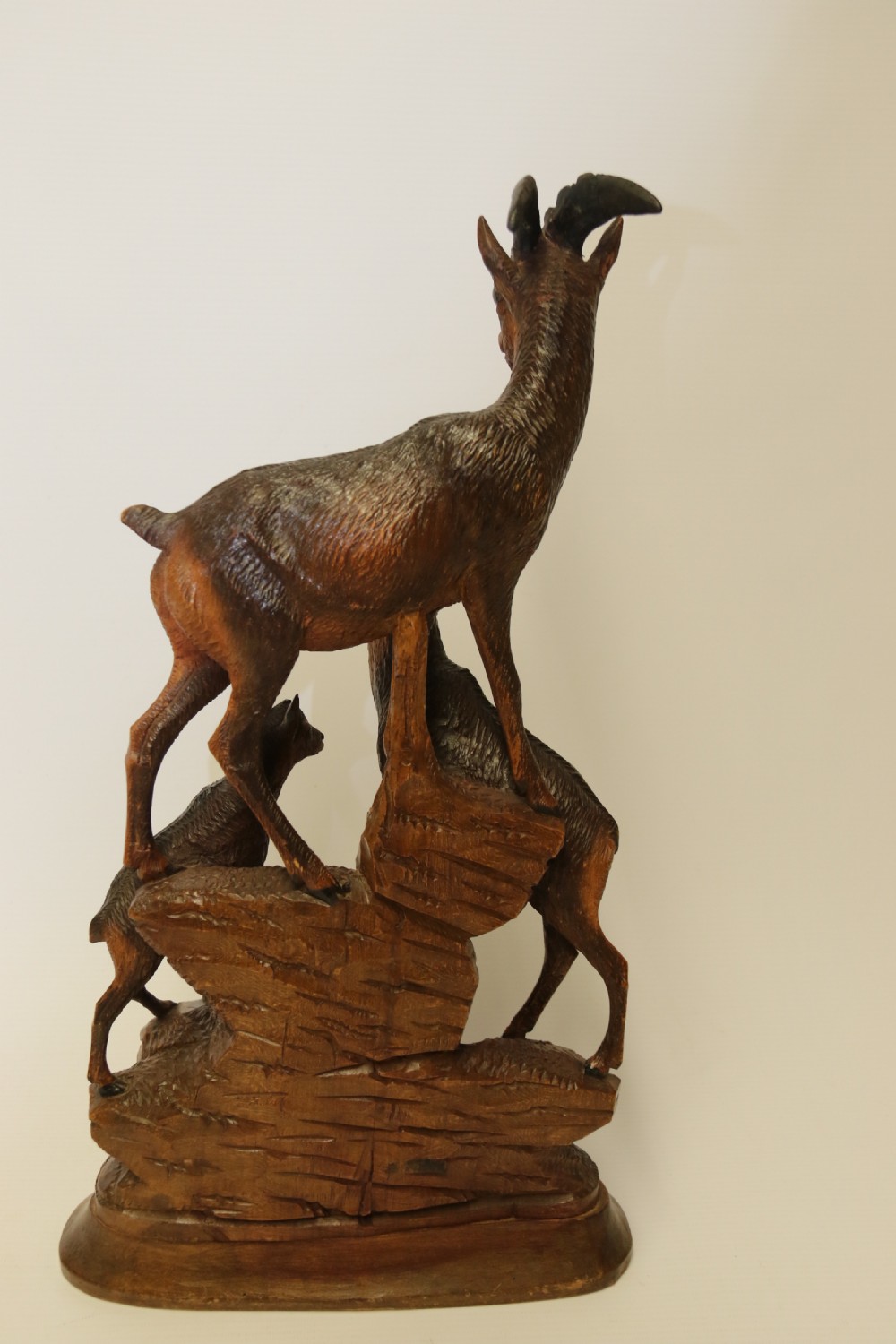 A pair of hand-carved wooden sculptures depicting ibex and chamois with offspring on carved rocky bases. View IX