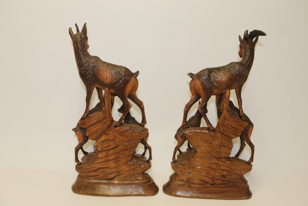 A pair of hand-carved wooden sculptures depicting ibex and chamois with offspring on carved rocky bases. View XIII