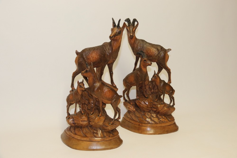 A pair of hand-carved wooden sculptures depicting ibex and chamois with offspring on carved rocky bases. View XIV