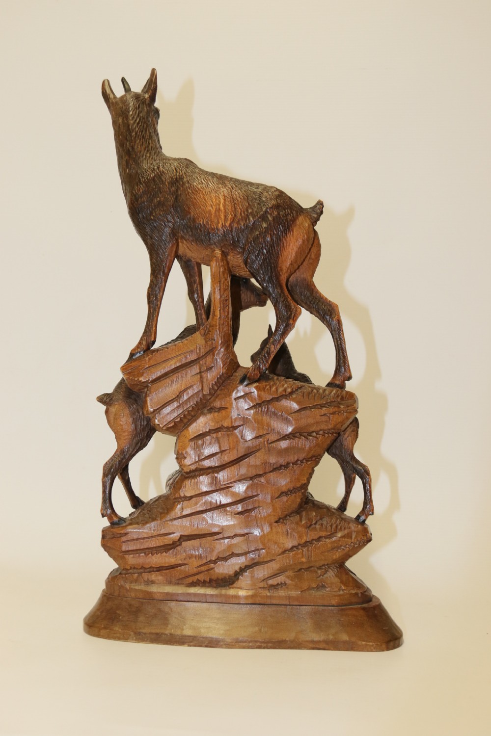 A pair of hand-carved wooden sculptures depicting ibex and chamois with offspring on carved rocky bases. View XIX