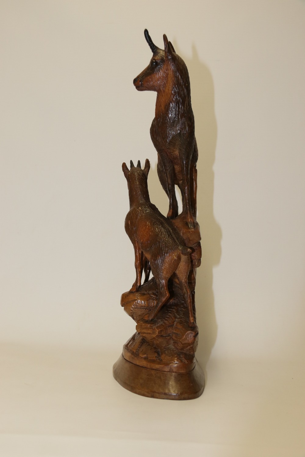 A pair of hand-carved wooden sculptures depicting ibex and chamois with offspring on carved rocky bases. View XXI