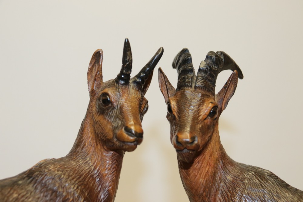 A pair of hand-carved wooden sculptures depicting ibex and chamois with offspring on carved rocky bases. View XXVII