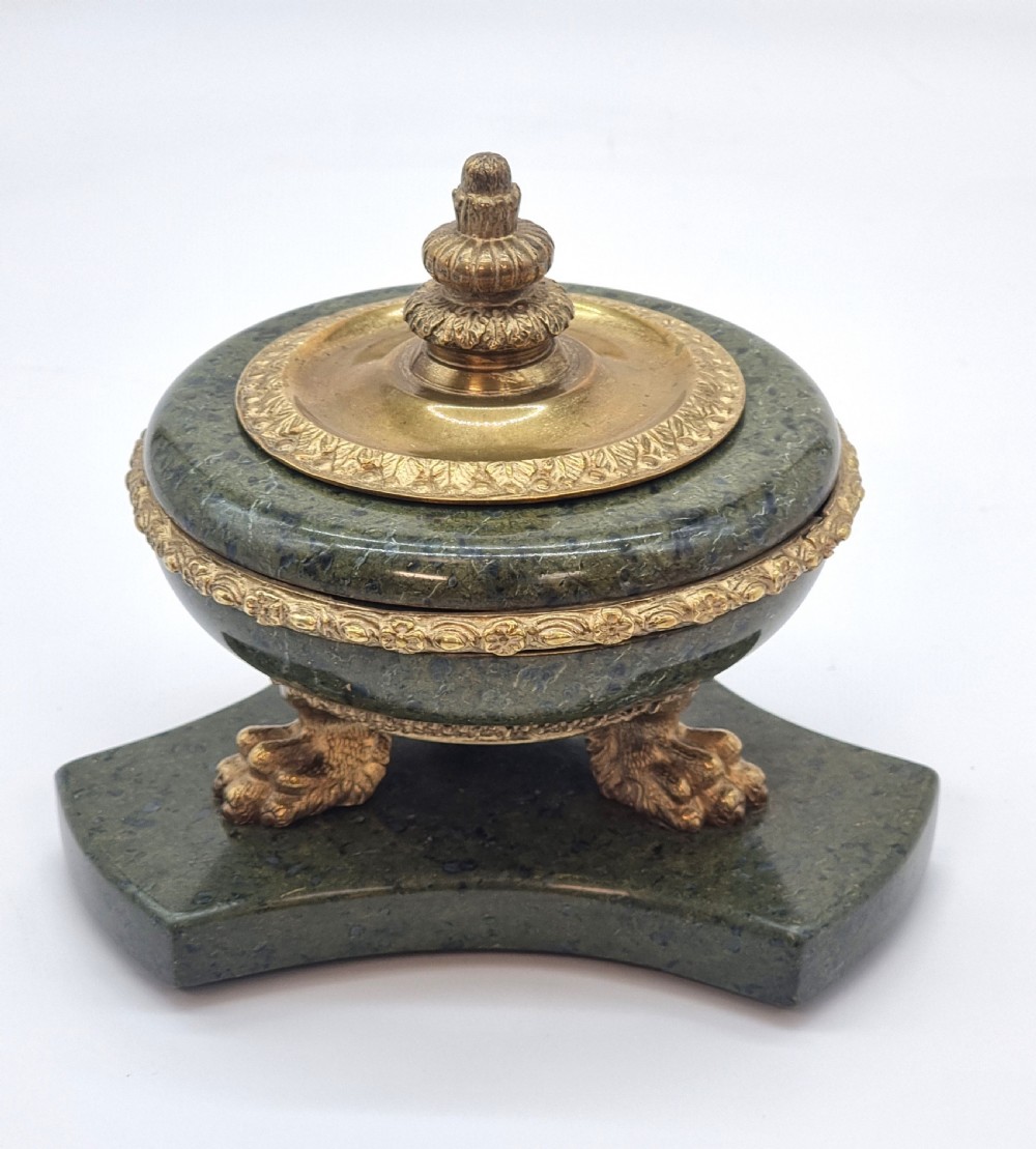 A French Empire style green marble inkstand featuring a central urn-shaped vessel with gilt bronze floral borders and a decorative finial lid, supported by three lion paw feet on a curved marble base. View III