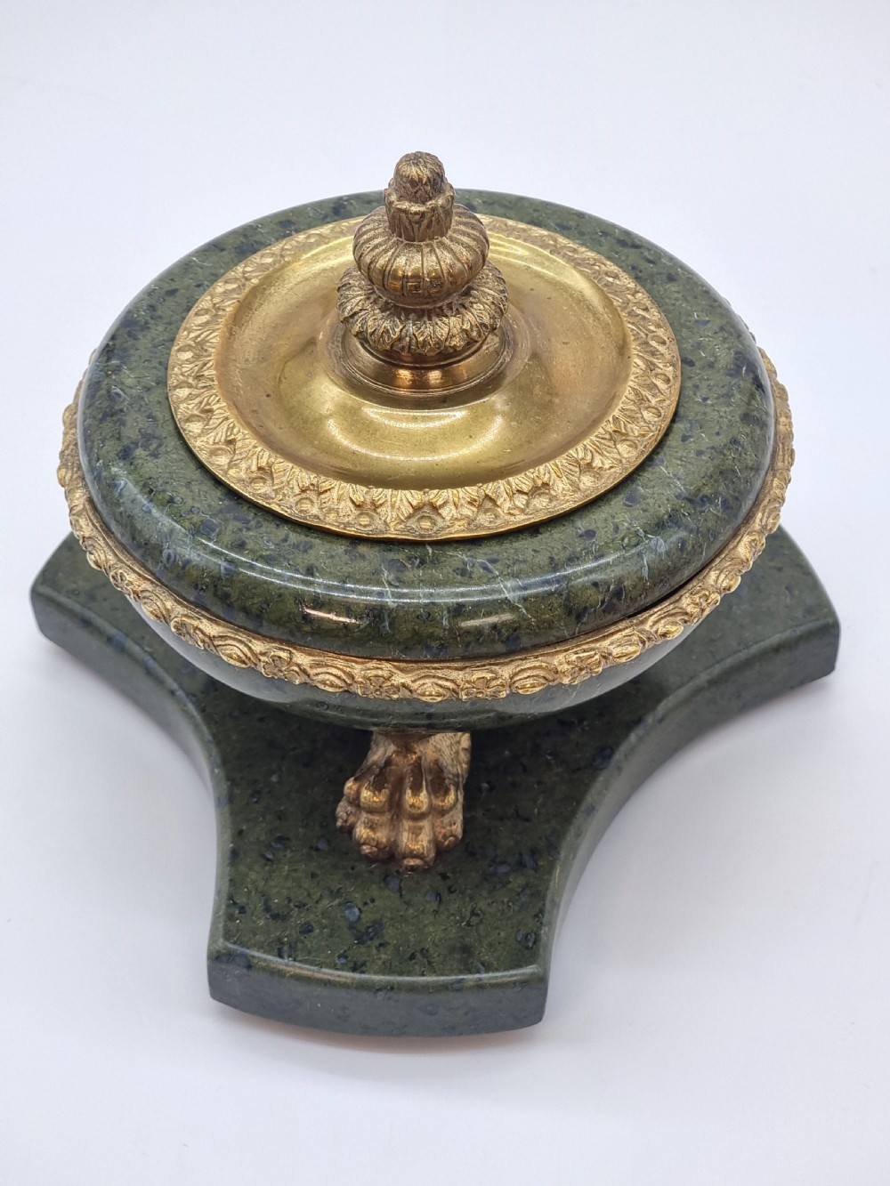 A French Empire style green marble inkstand featuring a central urn-shaped vessel with gilt bronze floral borders and a decorative finial lid, supported by three lion paw feet on a curved marble base. View VIII