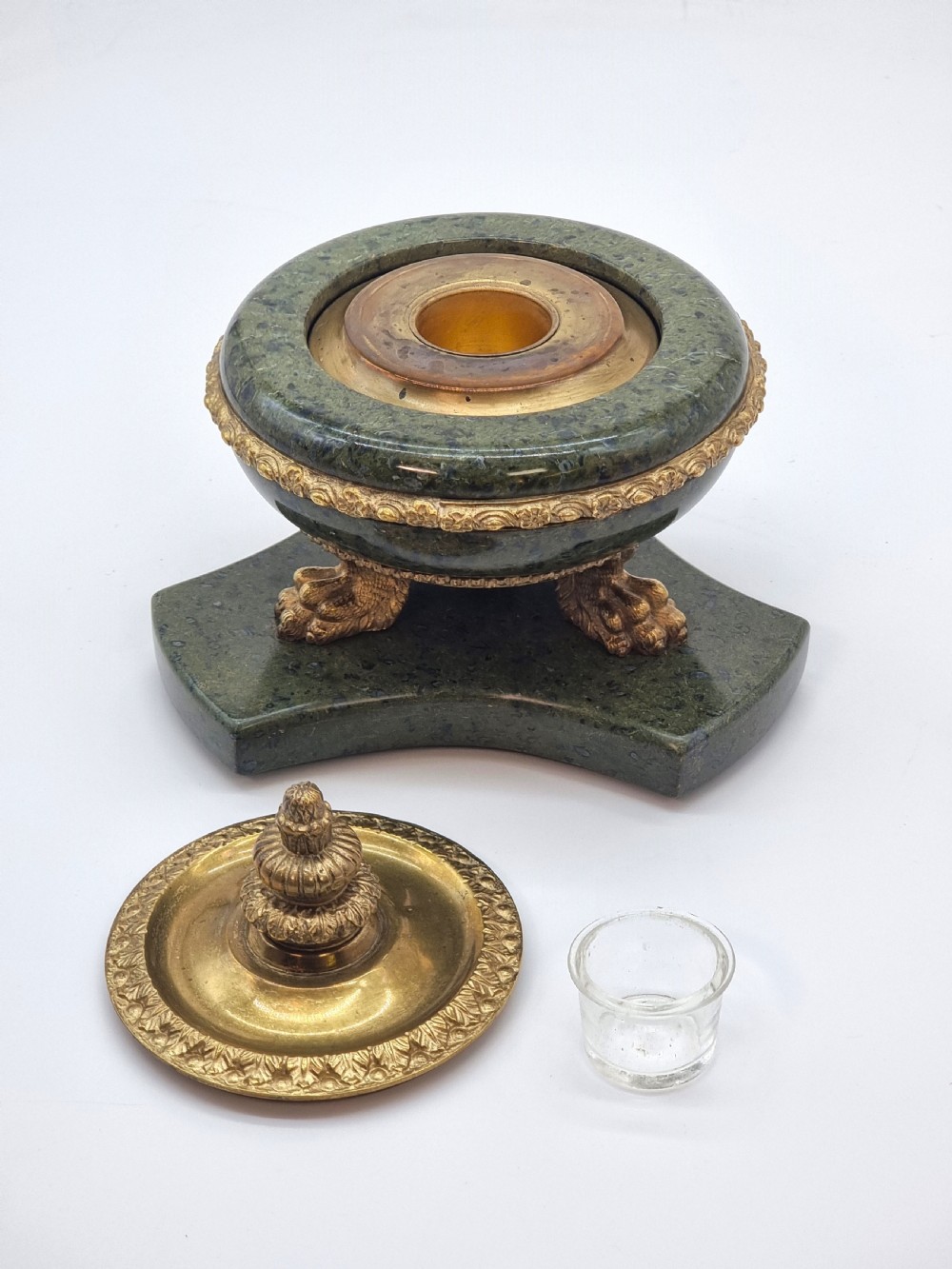 A French Empire style green marble inkstand featuring a central urn-shaped vessel with gilt bronze floral borders and a decorative finial lid, supported by three lion paw feet on a curved marble base. View XI