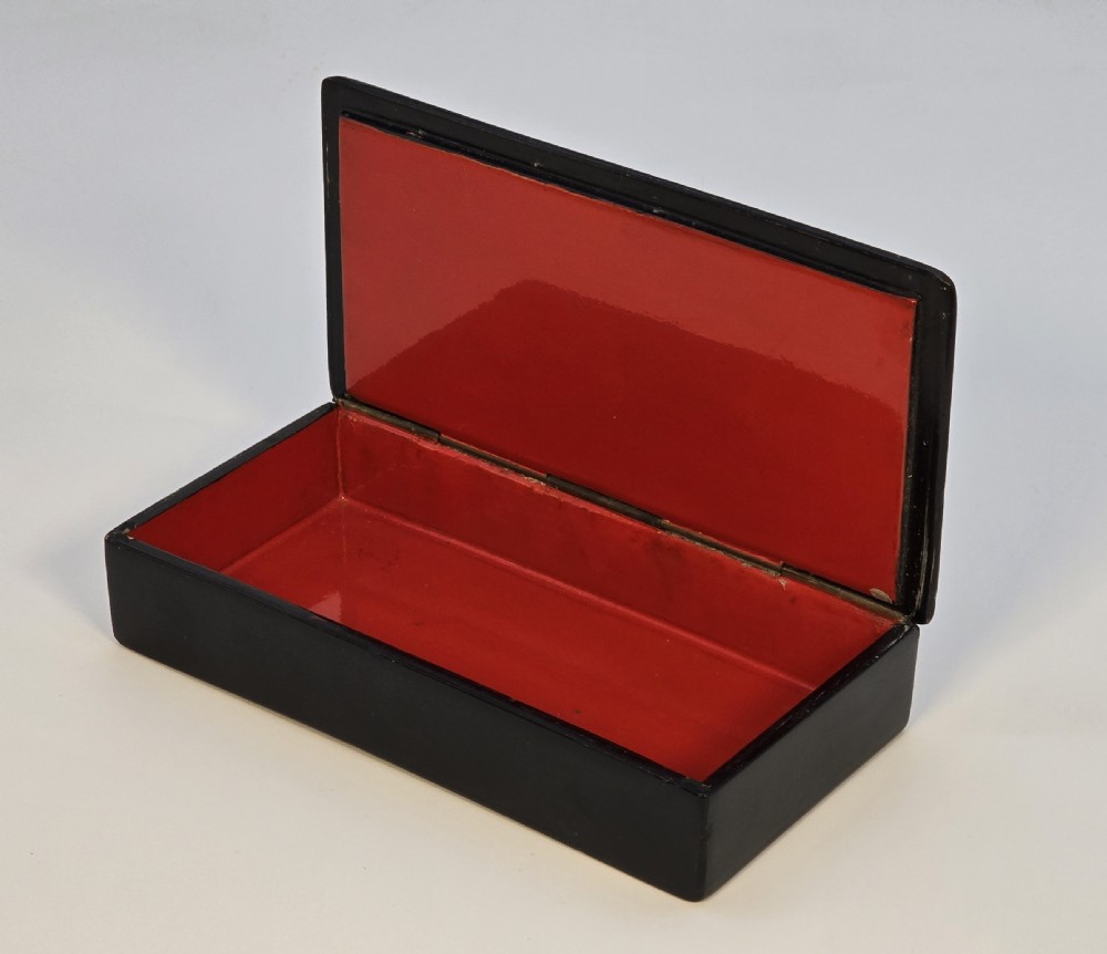 A rectangular black lacquered papier-mache box featuring a detailed hand-painted scene from Russian folklore framed by a delicate gold filigree border. View V