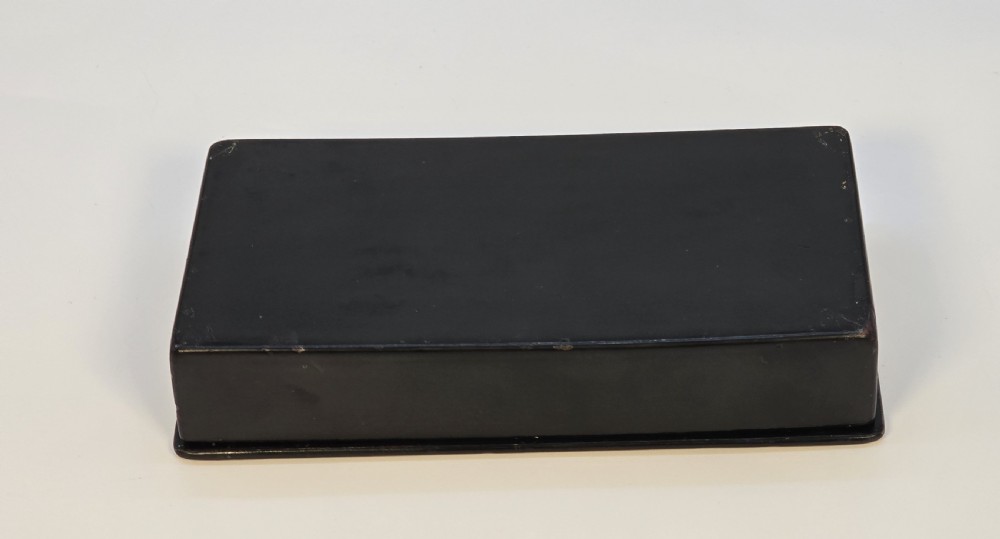 A rectangular black lacquered papier-mache box featuring a detailed hand-painted scene from Russian folklore framed by a delicate gold filigree border. View VII