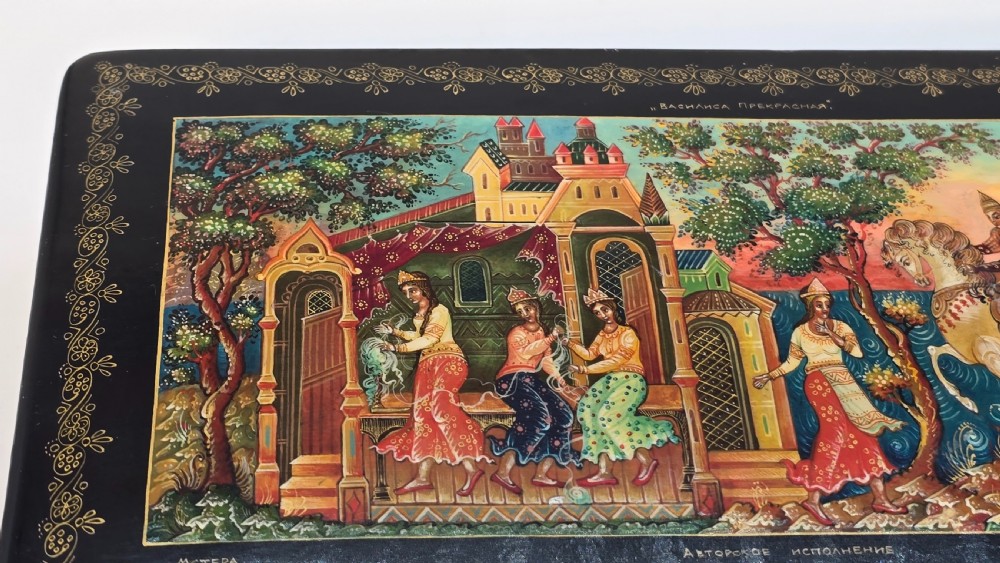 A rectangular black lacquered papier-mache box featuring a detailed hand-painted scene from Russian folklore framed by a delicate gold filigree border. View VIII