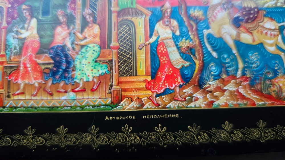 A rectangular black lacquered papier-mache box featuring a detailed hand-painted scene from Russian folklore framed by a delicate gold filigree border. View XV