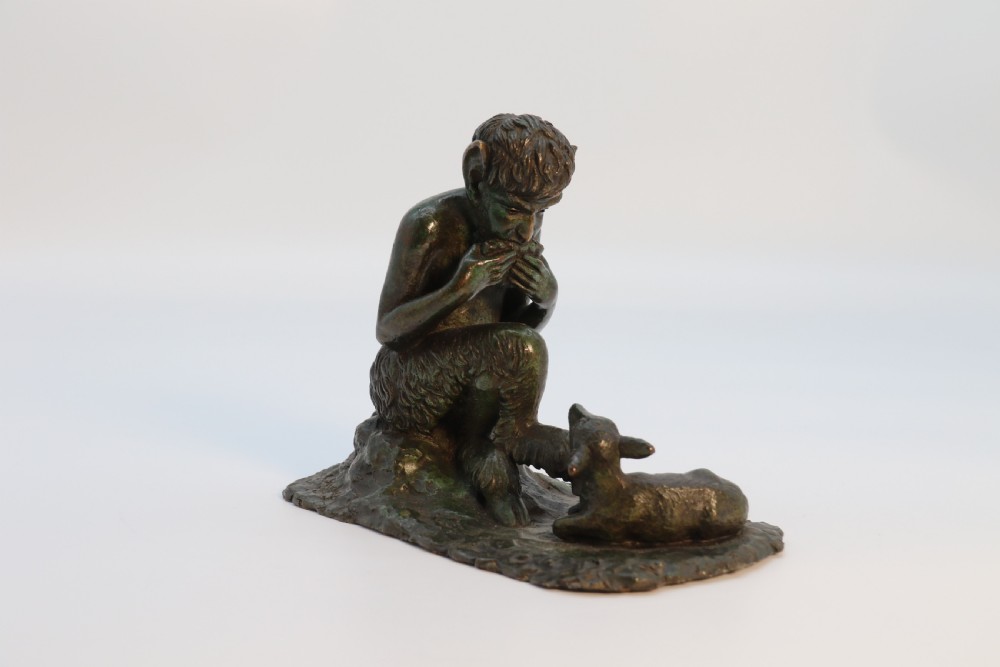 A dark brown patinated bronze sculpture depicting the mythological figure Pan crouching while playing panpipes to a small fawn sitting before him. View V