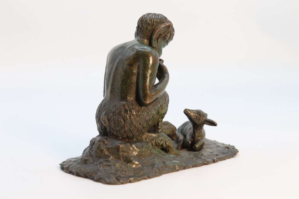 A dark brown patinated bronze sculpture depicting the mythological figure Pan crouching while playing panpipes to a small fawn sitting before him. View VII