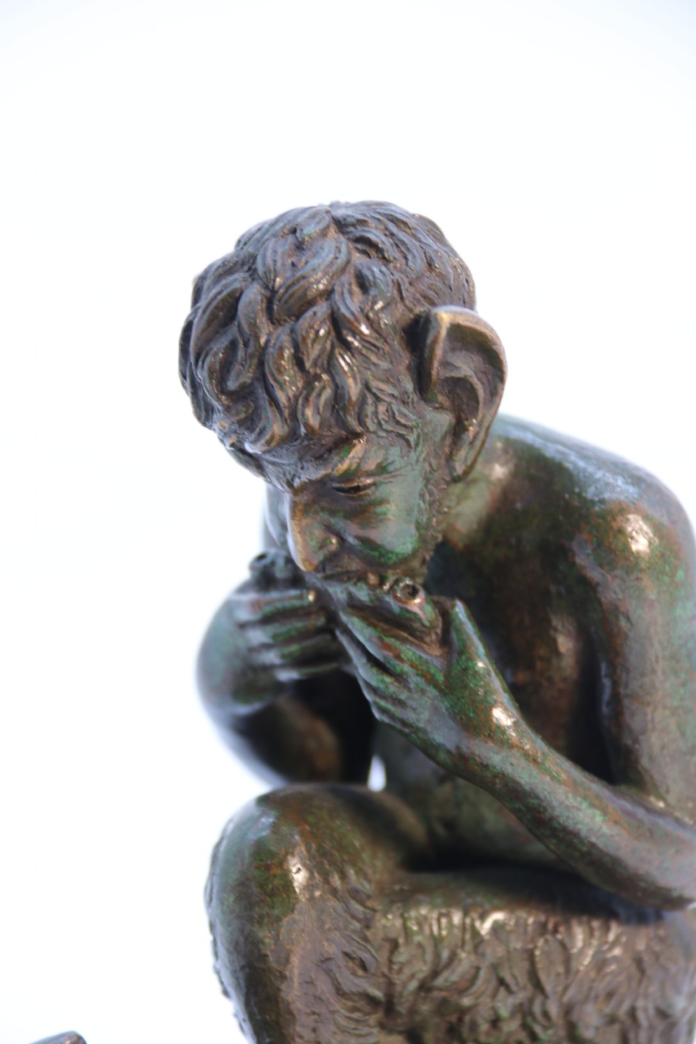 A dark brown patinated bronze sculpture depicting the mythological figure Pan crouching while playing panpipes to a small fawn sitting before him. View XI