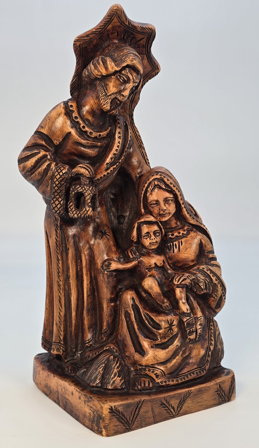 A carved olive wood sculpture depicting Saint Joseph, Mary, and the infant Jesus on an incised wooden base.
